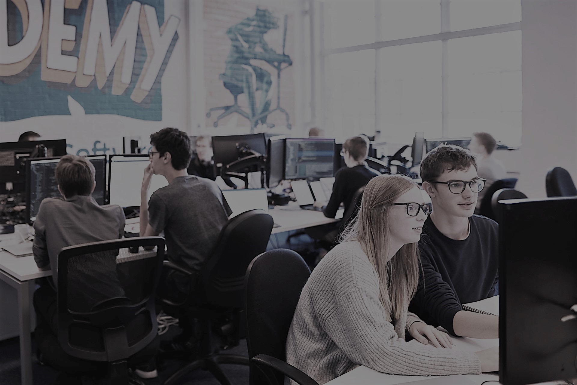 Learners pairing on a software development exercise at a computer. Woman on the left, man on the right.